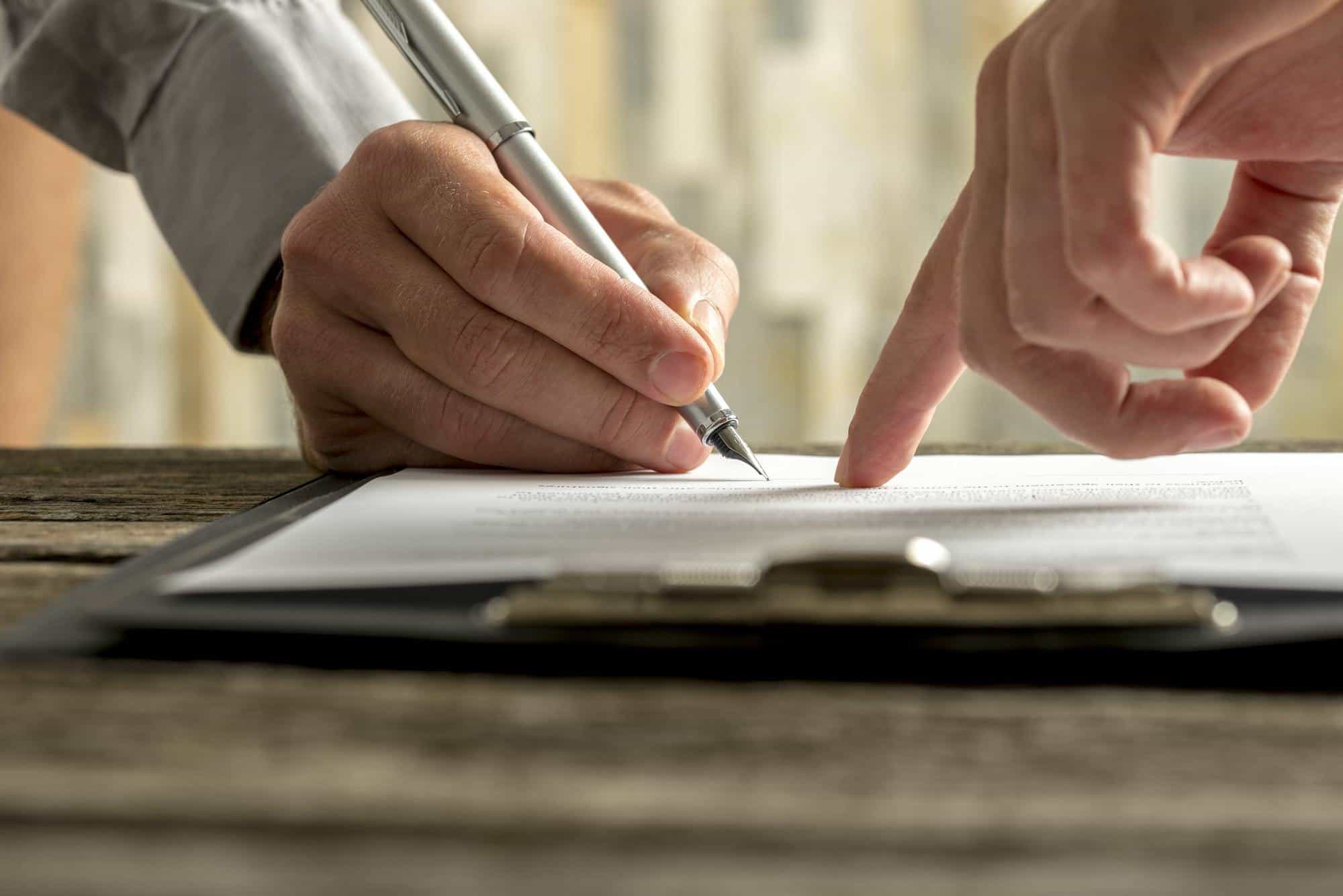 Closeup of employer showing his new employee where to sign an employment contract